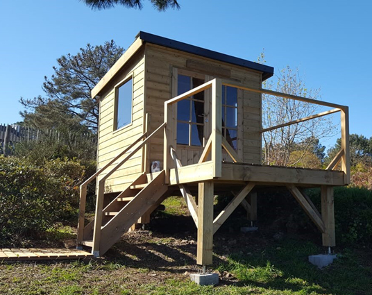 Cabane en bois surélevée avec terrasse.