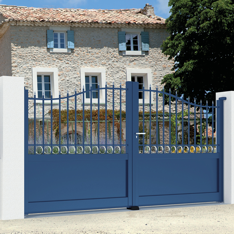 Portail bleu devant maison en pierre.